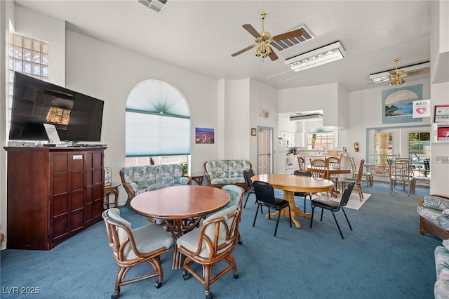 carpeted dining room with a ceiling fan, a towering ceiling, and a wealth of natural light