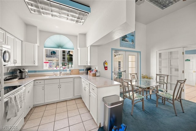kitchen with range with electric cooktop, a sink, light tile patterned floors, stainless steel microwave, and a peninsula