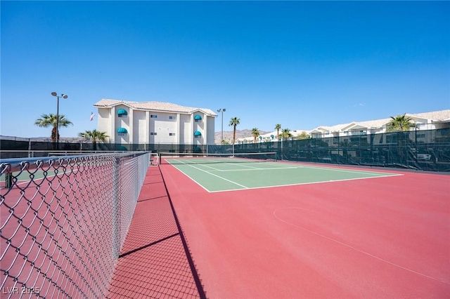 view of tennis court featuring community basketball court and fence