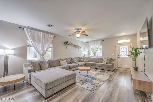 living room featuring ceiling fan, wood finished floors, and visible vents