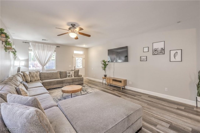living area with a ceiling fan, baseboards, visible vents, and wood finished floors