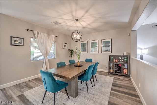 dining space with visible vents, baseboards, wood finished floors, and a chandelier