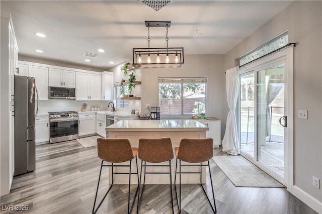 kitchen with visible vents, light countertops, white cabinets, light wood finished floors, and stainless steel appliances