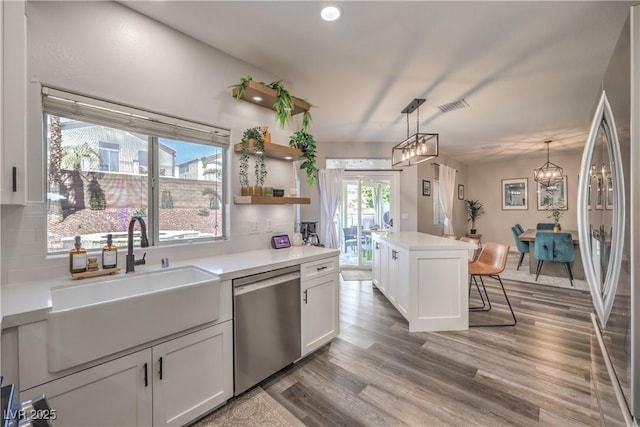 kitchen featuring pendant lighting, a sink, a notable chandelier, stainless steel appliances, and white cabinetry