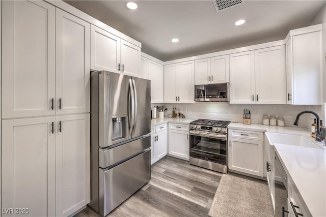 kitchen with visible vents, appliances with stainless steel finishes, a sink, light countertops, and white cabinets