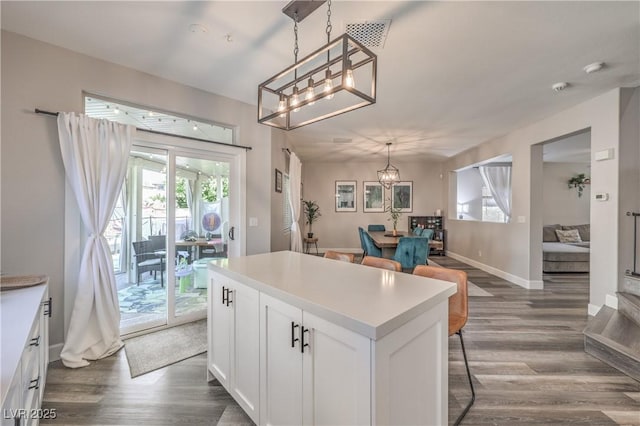 kitchen featuring white cabinets, a kitchen island, dark wood finished floors, and a chandelier