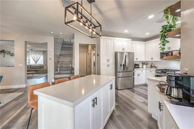 kitchen with a kitchen island, appliances with stainless steel finishes, light countertops, recessed lighting, and white cabinetry