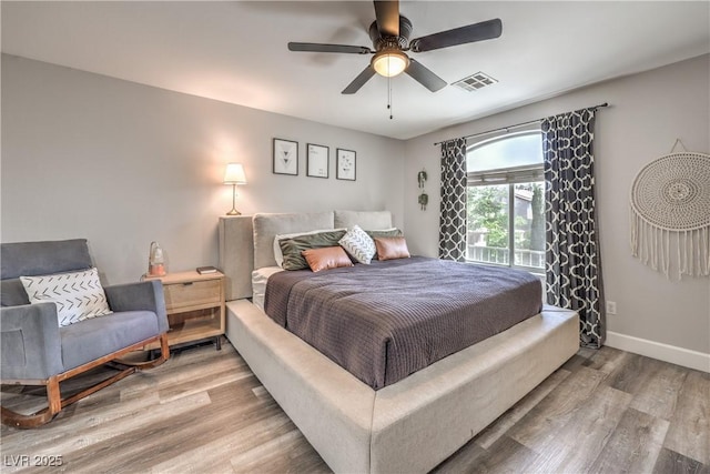 bedroom with baseboards, visible vents, ceiling fan, and light wood-style floors