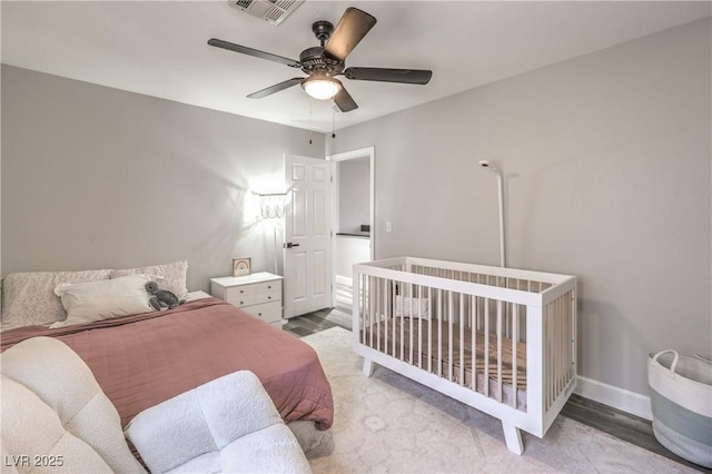 bedroom featuring baseboards, ceiling fan, visible vents, and wood finished floors