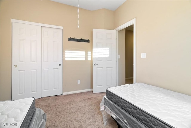 carpeted bedroom with a closet and baseboards