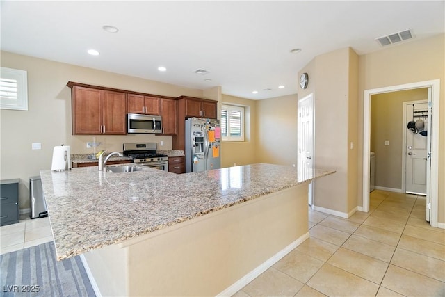 kitchen with visible vents, light tile patterned flooring, light stone countertops, a sink, and stainless steel appliances