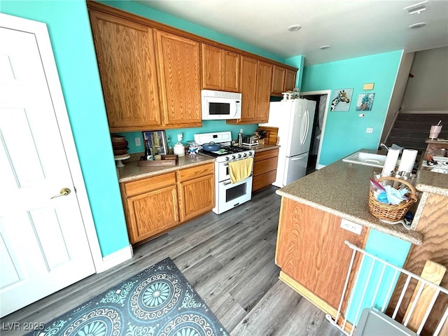 kitchen with white appliances, brown cabinets, and wood finished floors