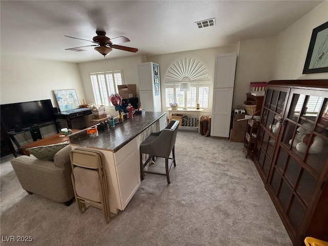 office area with a ceiling fan, light colored carpet, and visible vents