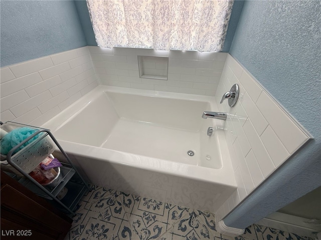 full bathroom featuring a textured wall and a bath