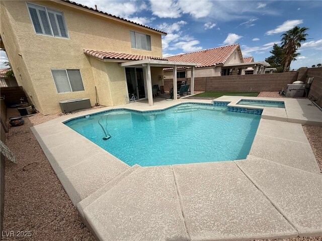 view of swimming pool featuring a patio, a fenced backyard, and a pool with connected hot tub