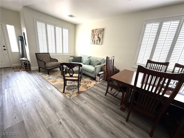 living room with baseboards, visible vents, and wood finished floors