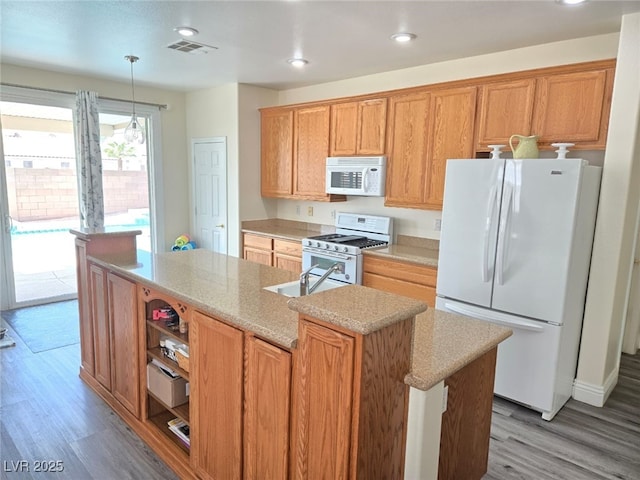 10071 Lemon Valley Ave, Las Vegas, NV 89147 - kitchen featuring white appliances, wood finished floors, a center island with sink, recessed lighting, and hanging light fixtures