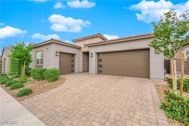 prairie-style house with a garage, fence, stucco siding, and driveway