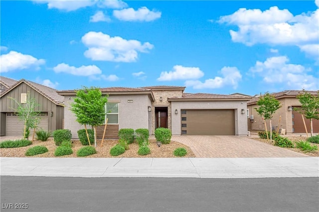 prairie-style house featuring a garage, stucco siding, driveway, and a tile roof