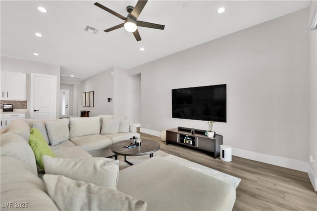 living area featuring a ceiling fan, baseboards, visible vents, and light wood-type flooring