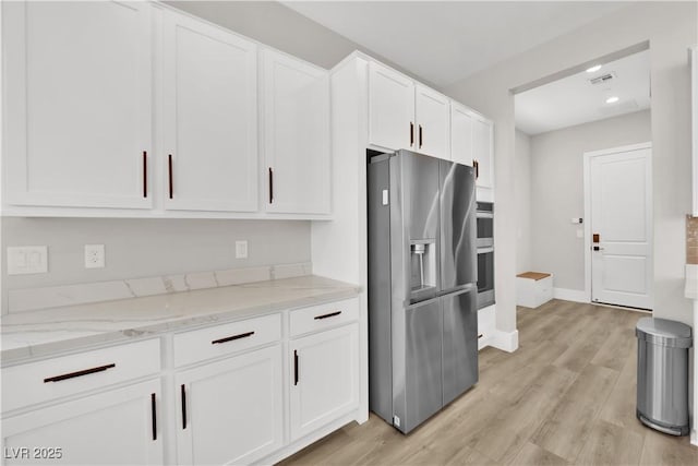 kitchen with visible vents, white cabinetry, light stone counters, and stainless steel appliances