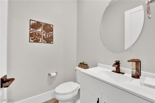 half bath featuring vanity, baseboards, and toilet