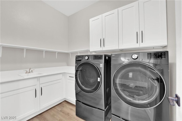 laundry room featuring a sink, light wood-style floors, cabinet space, and washer and dryer