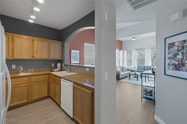 kitchen with white appliances, arched walkways, a sink, and light wood-type flooring