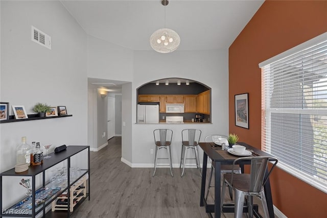dining area featuring baseboards, visible vents, wood finished floors, and an inviting chandelier