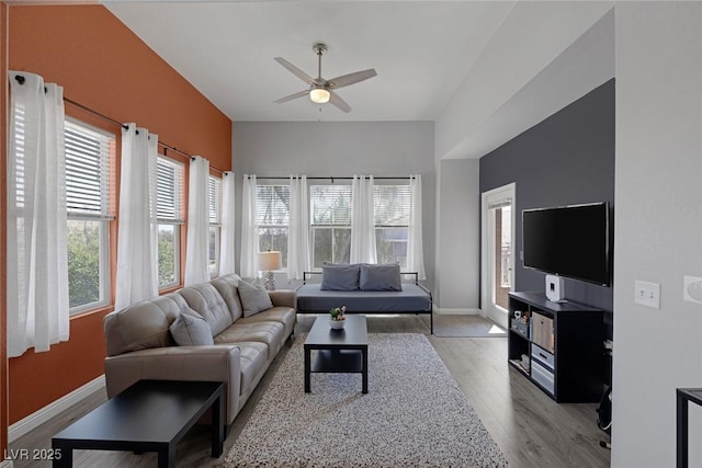 living area with ceiling fan, a wealth of natural light, and wood finished floors