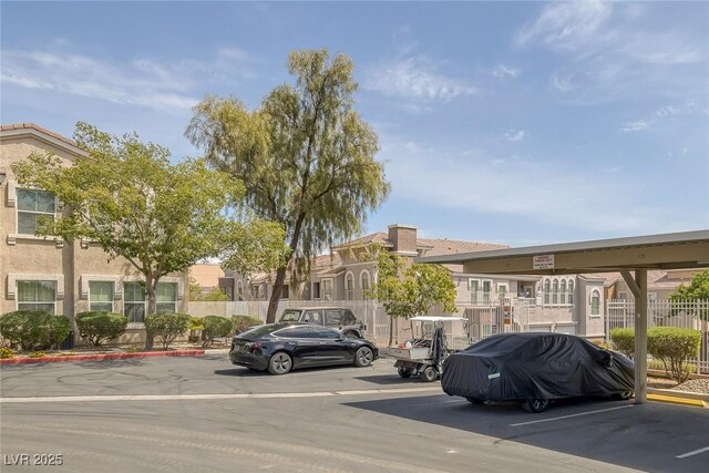 partially covered parking lot featuring fence and a residential view