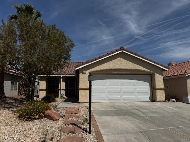 single story home with concrete driveway, a tiled roof, stucco siding, and a garage