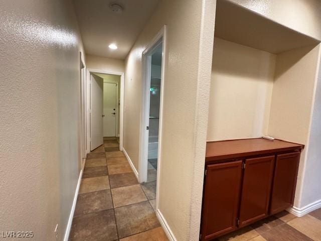 hallway with recessed lighting, baseboards, a textured wall, and tile patterned floors