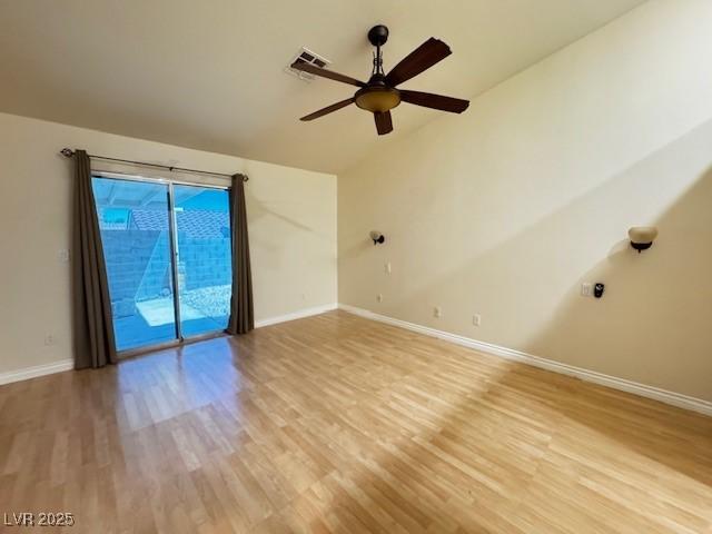 spare room featuring baseboards, visible vents, light wood-style flooring, and lofted ceiling