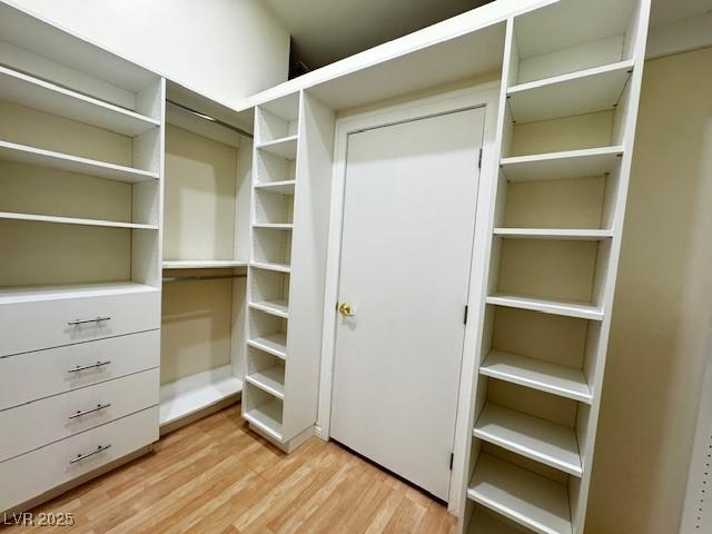 walk in closet with light wood-style floors