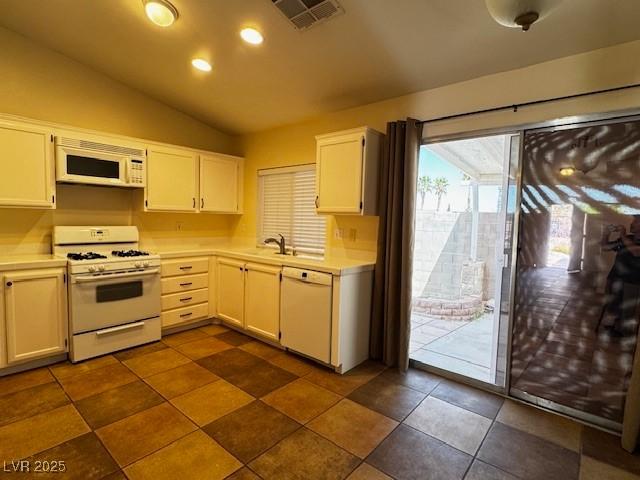 kitchen with visible vents, light countertops, lofted ceiling, and white appliances