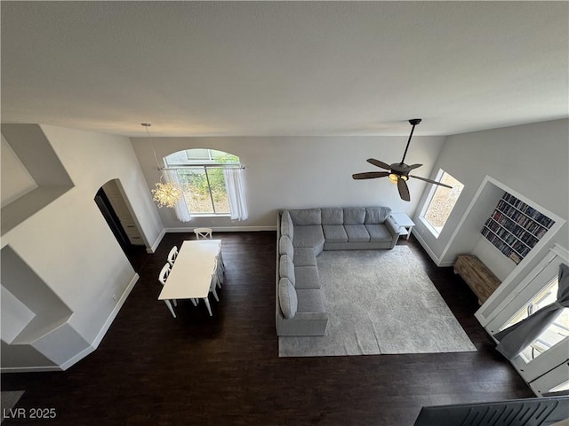 living room with lofted ceiling, dark wood-style floors, arched walkways, and ceiling fan