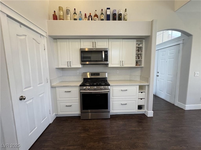 kitchen with stainless steel appliances, open shelves, light countertops, and white cabinetry