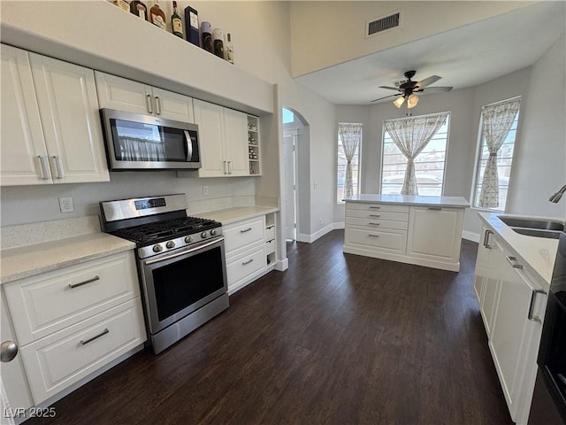 kitchen with appliances with stainless steel finishes, dark wood-type flooring, a ceiling fan, and white cabinetry