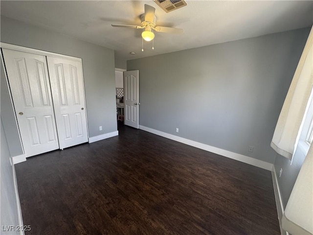 unfurnished bedroom featuring dark wood-type flooring, a closet, and a ceiling fan