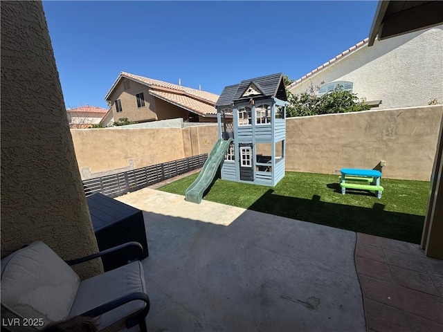 fenced backyard with a playground and a patio area