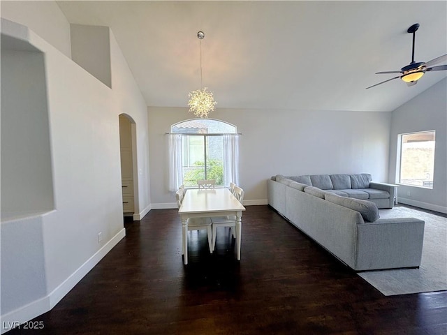 living area featuring dark wood-style flooring, arched walkways, baseboards, and plenty of natural light