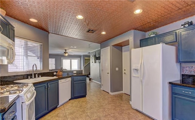 kitchen featuring blue cabinets, visible vents, dark countertops, a sink, and white appliances