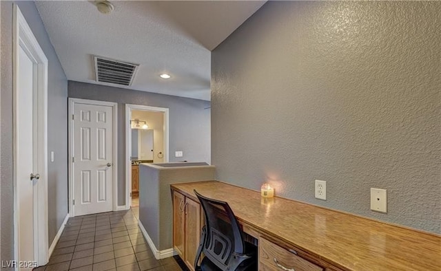 home office featuring visible vents, a textured wall, baseboards, and dark tile patterned flooring