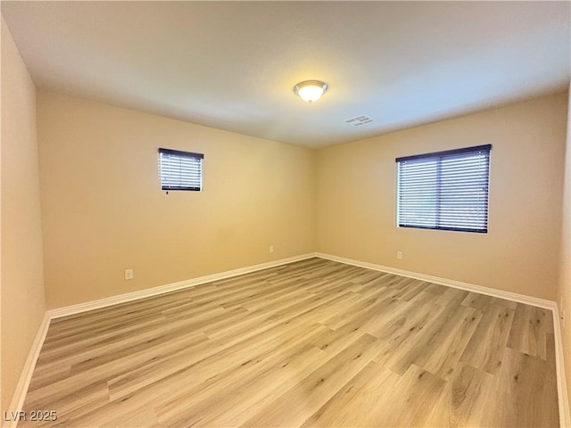spare room with baseboards, light wood-type flooring, and visible vents