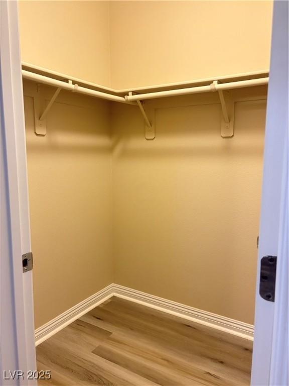 walk in closet with wood finished floors