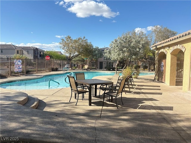 community pool with a patio area and fence