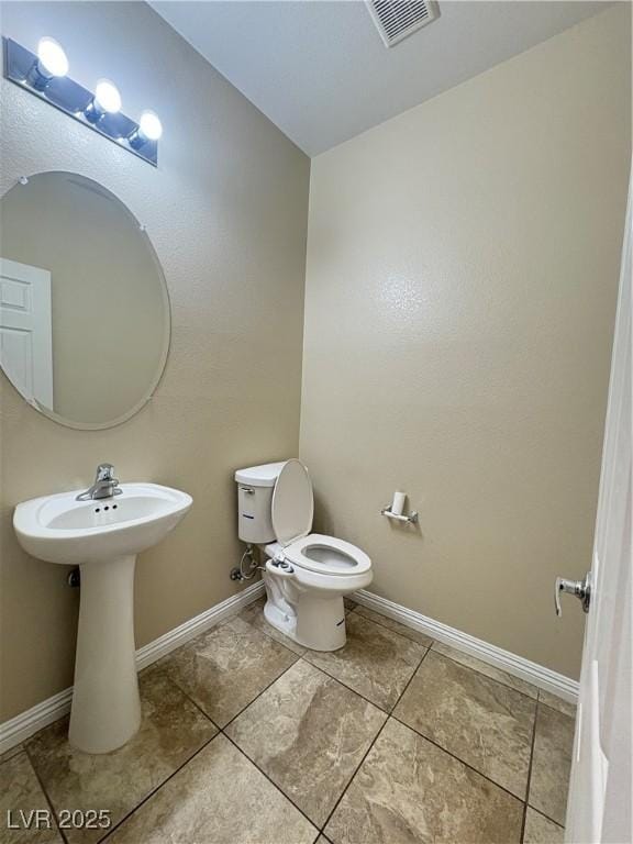 bathroom with a sink, baseboards, toilet, and visible vents