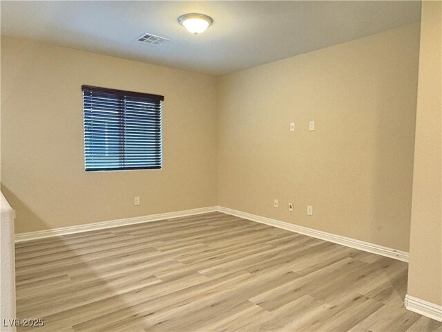 spare room featuring baseboards, wood finished floors, and visible vents