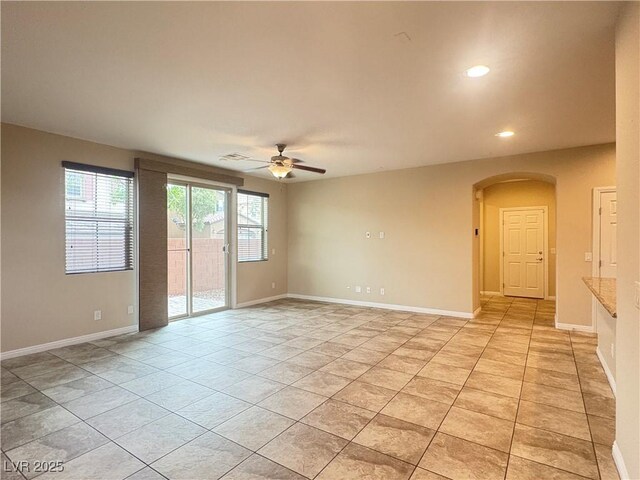 spare room with arched walkways, a ceiling fan, recessed lighting, baseboards, and light tile patterned floors